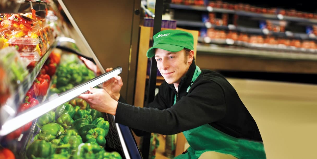 An image of a Sobeys teammate arranging all the vegetables and the lights of the vegetable section.